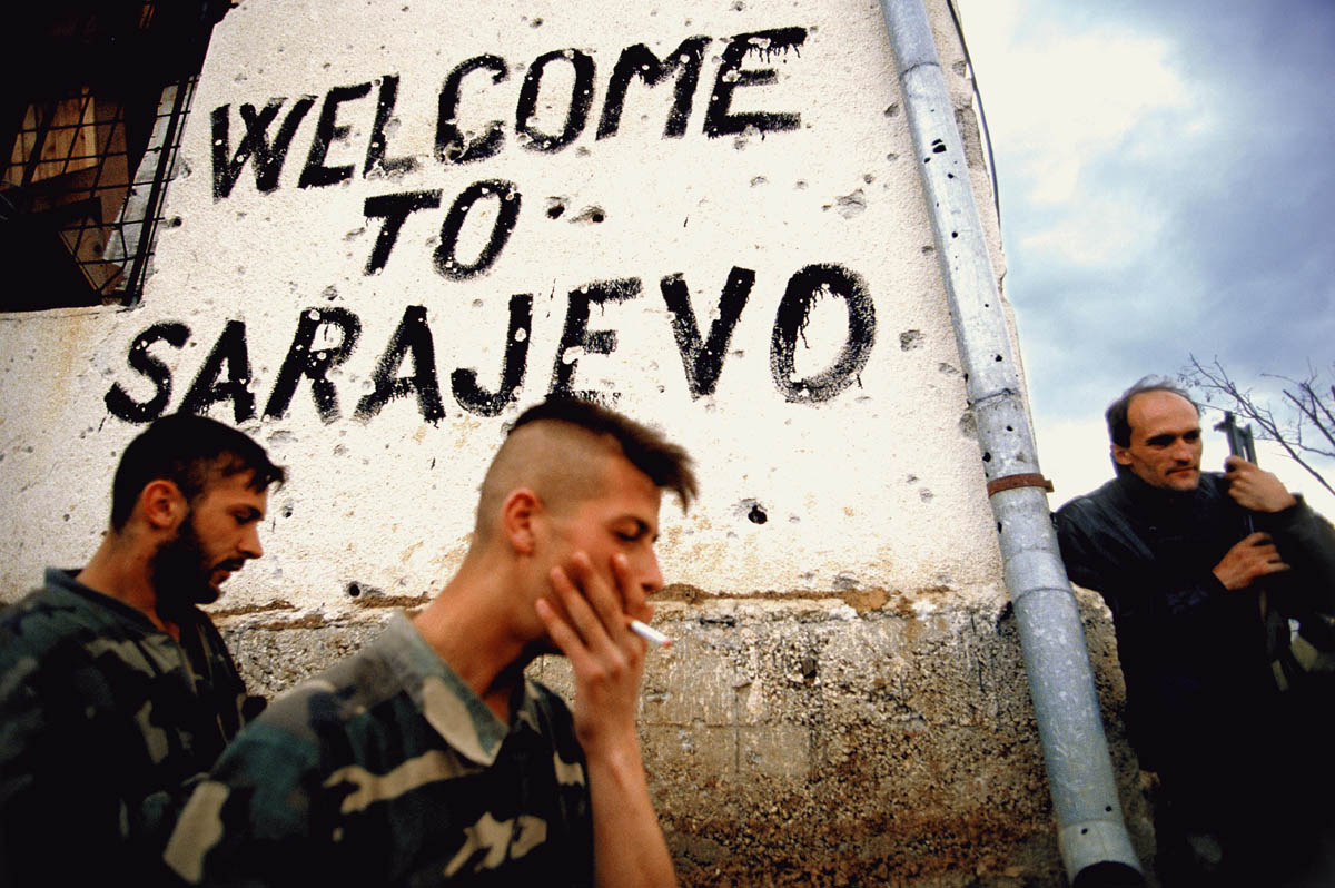 Bosnian soldiers smoke and take a break on the frontline next to a sign that says 'welcome to Sarajevo' in Sarajevo, Bosnia, in the fall of 1994. Trench warfare was fought all around the city of Sarajevo.